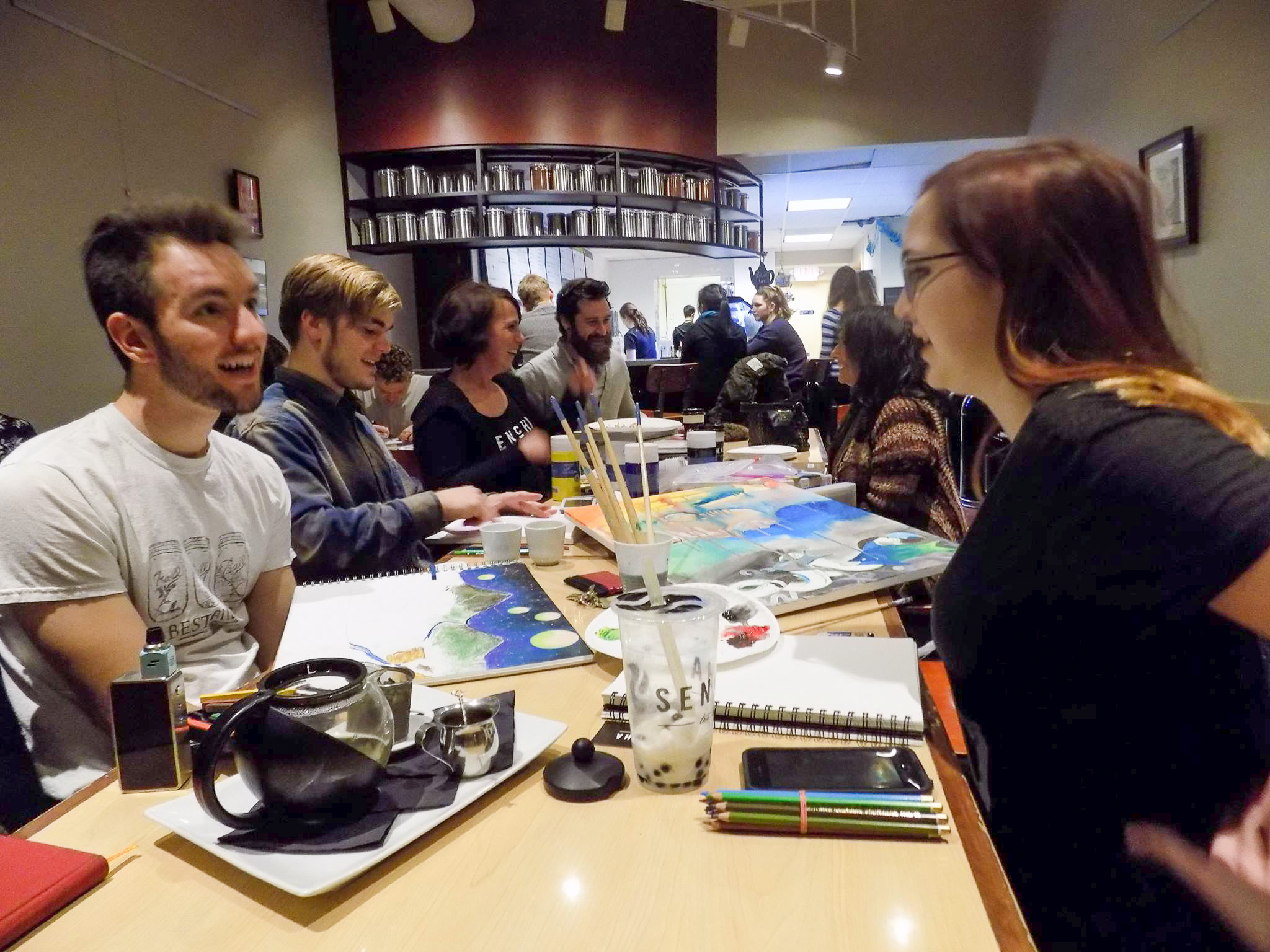 table with people socializing and making art at indoor art event