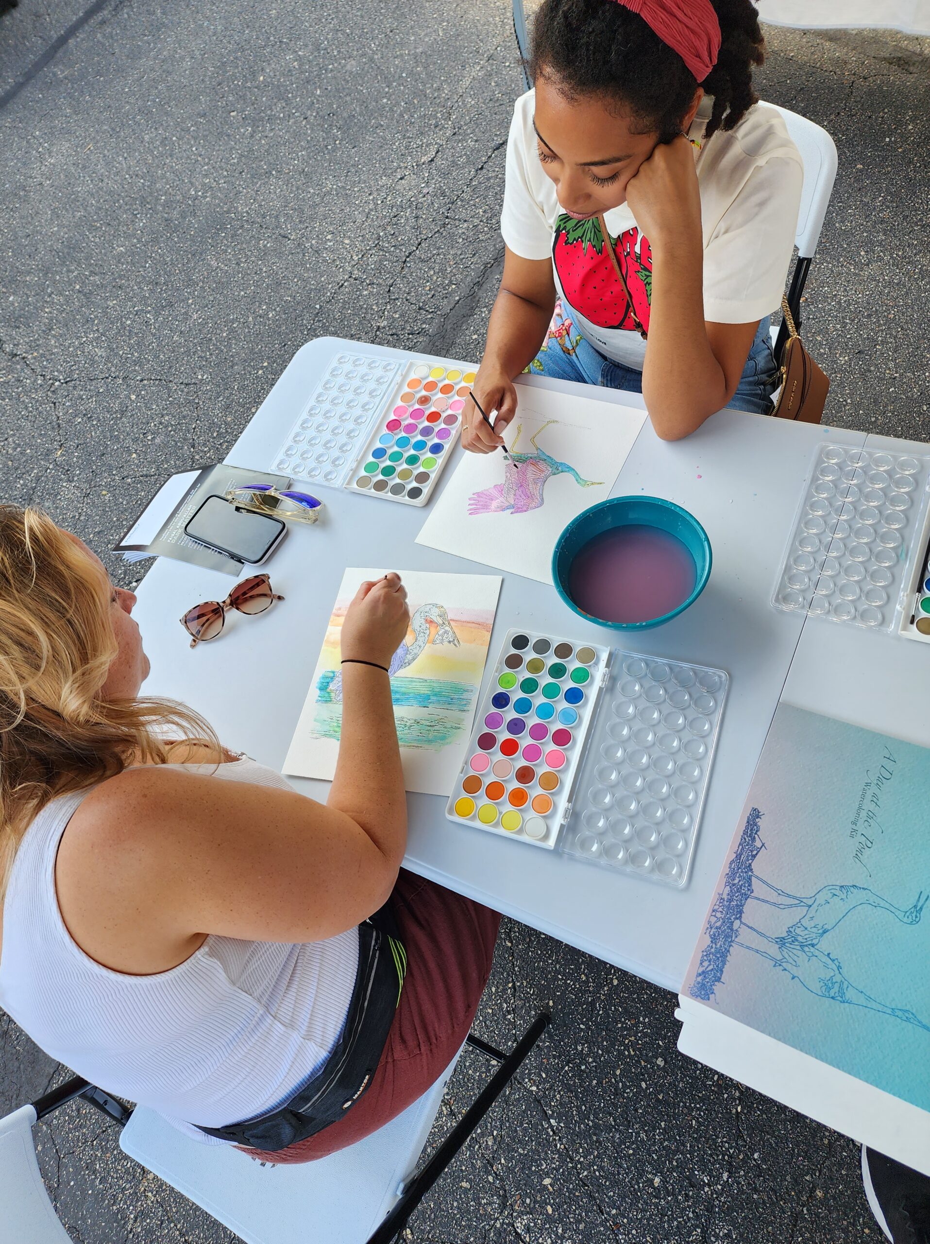 overhead view of two people across table watercoloring crane drawings