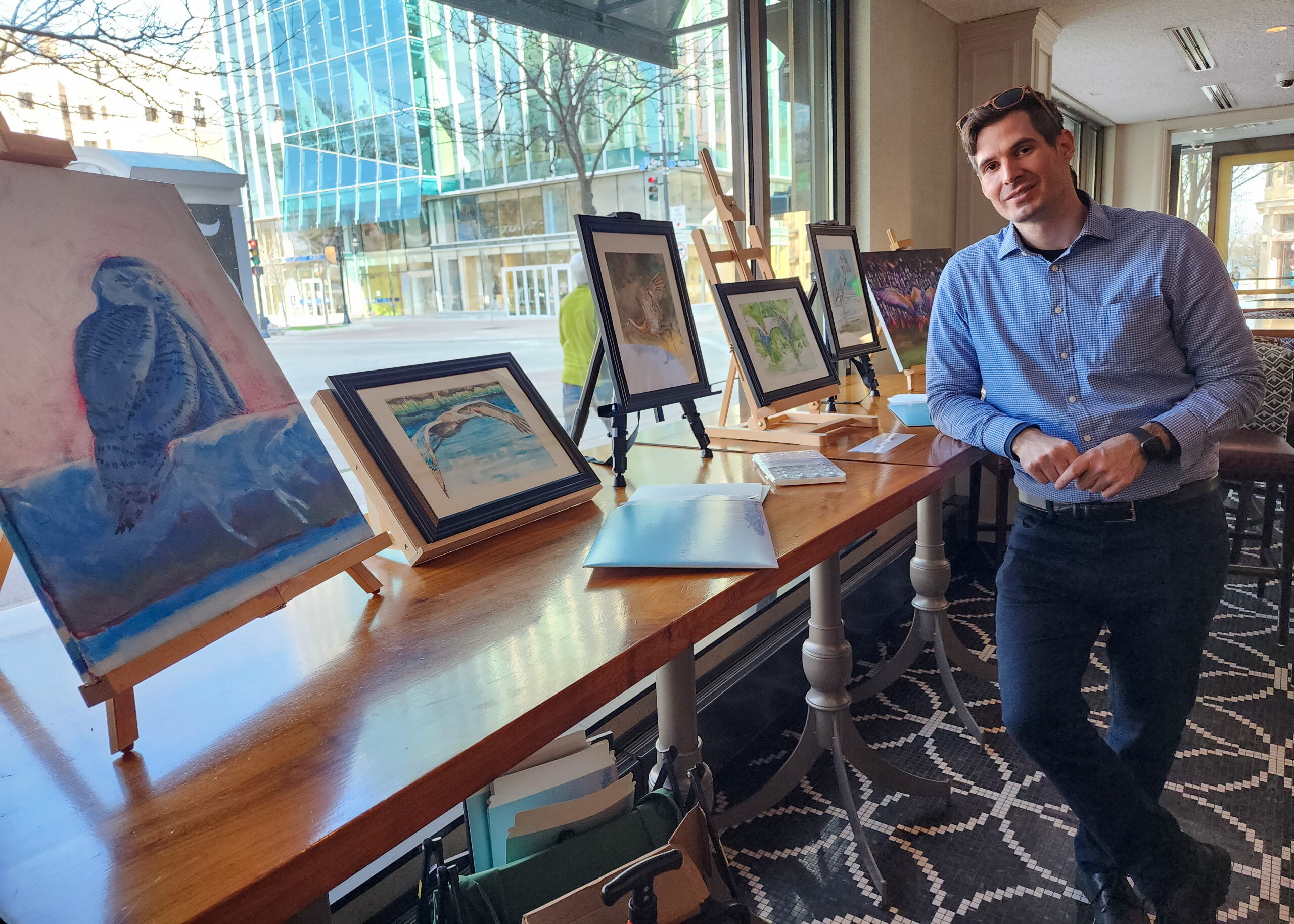 Artist Theo Howard with his bird paintings set up at an art show