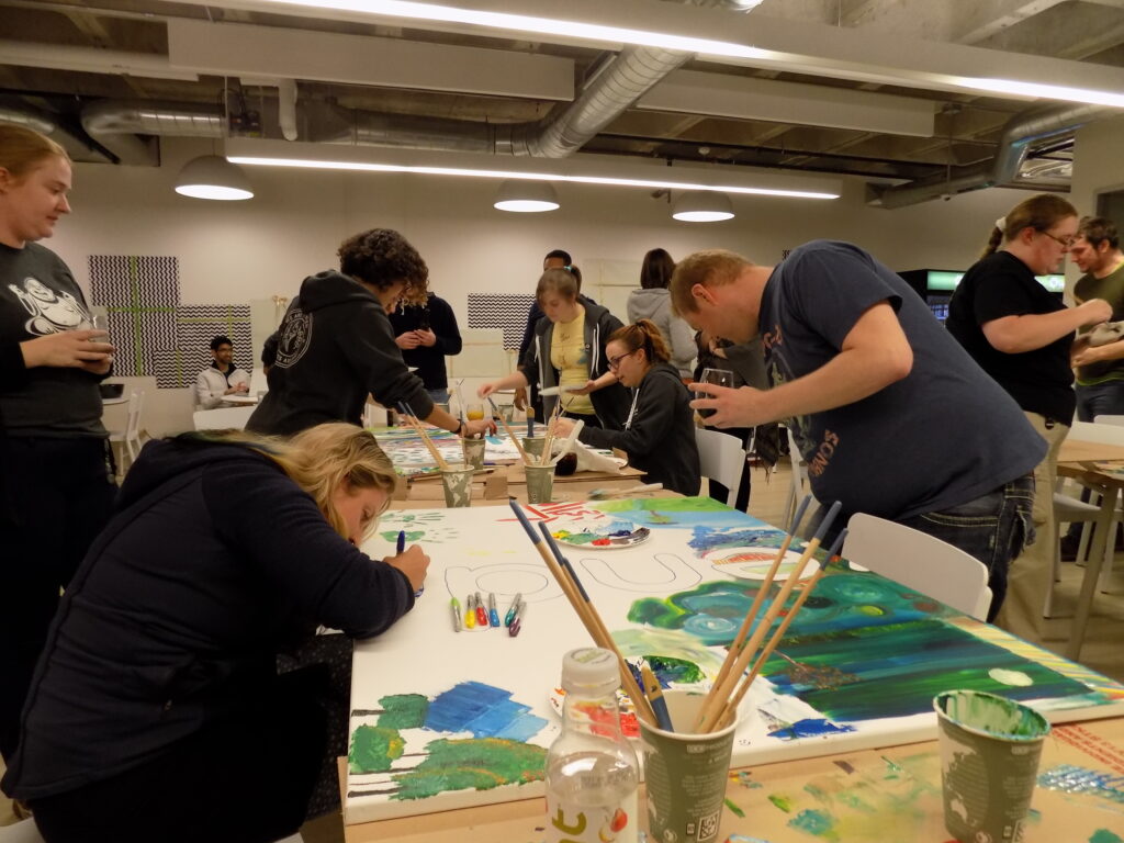 coworkers after work participating in collaborative painting at office team building activity